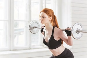 Woman lifting barbell resting on her shoulders